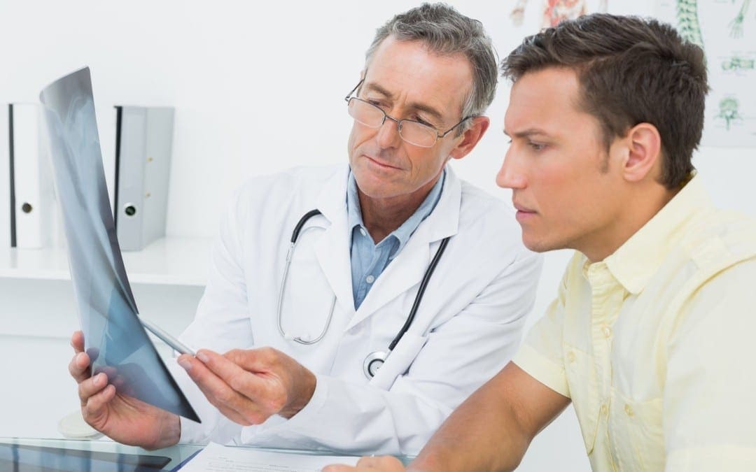 Doctor explains arthritis diagnosis on patient's x-rays.
